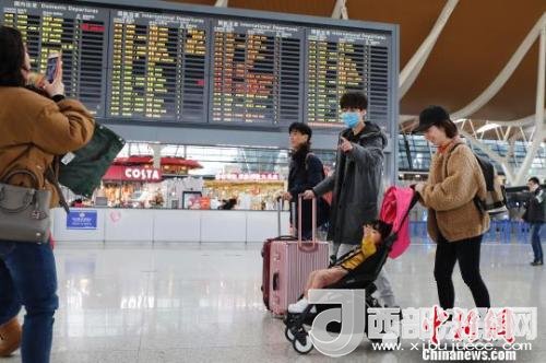 旅客帶著孩子前往辦票柜臺辦理登機手續(xù)?！∫罅⑶?攝